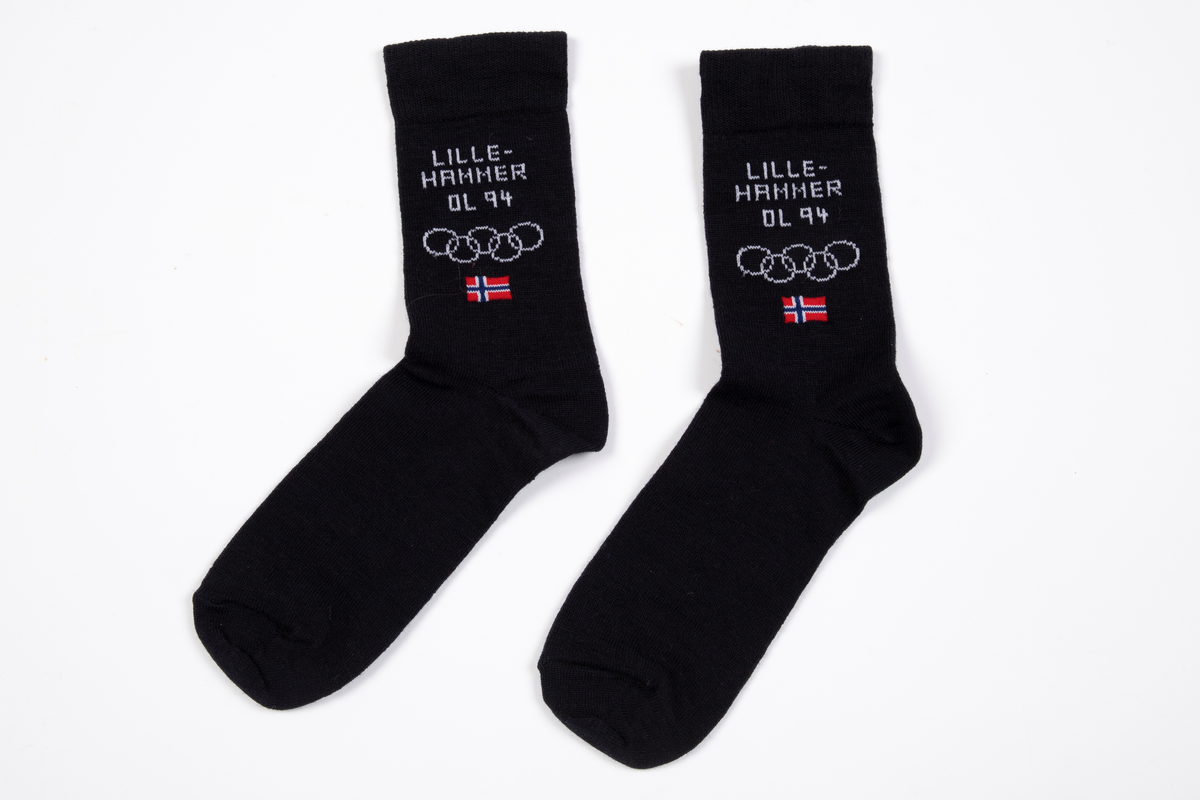 Et par sokker strikket i mørkeblått ullgarn. Innstrikket på begge sider med hvitt LILLEHAMMER OL, de olympiske ringer, samt norsk flagg i farger.