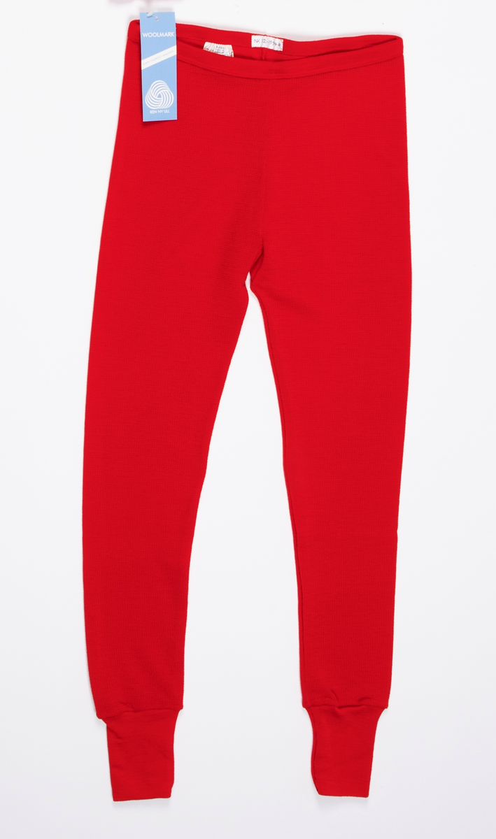 Longs i mønsterstrikket rødt ullgarn. Strikk i livet. Lange ben, trange ved ankelen med påsydd dobbelt glattstrikk. En søm på innsiden av hvert ben.