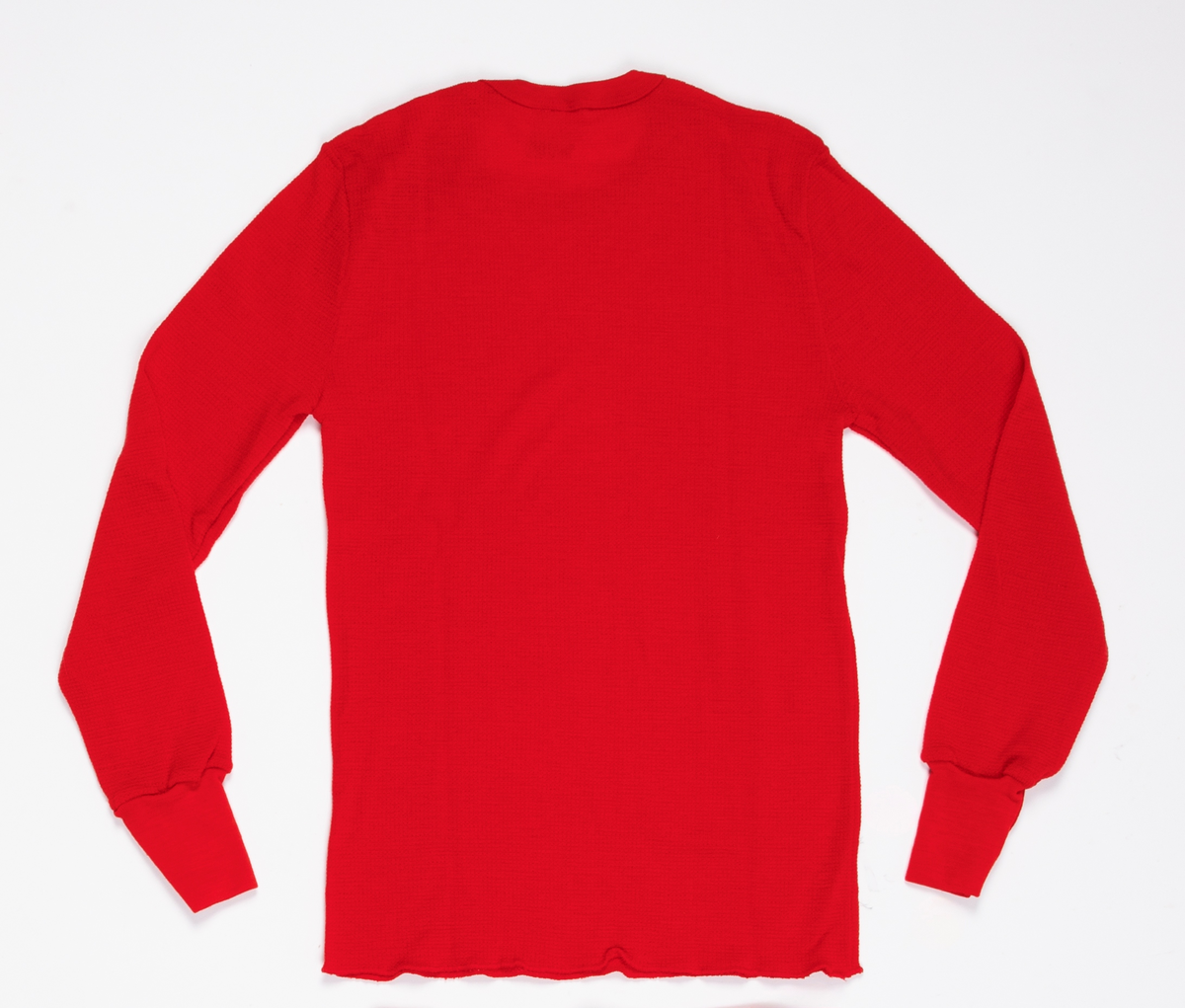 Trøye i mønsterstrikket rødt ullgarn. Søm i hver side. Rund hals. Lange, isydde ermer med mansjett i dobbelt glattstrikk.