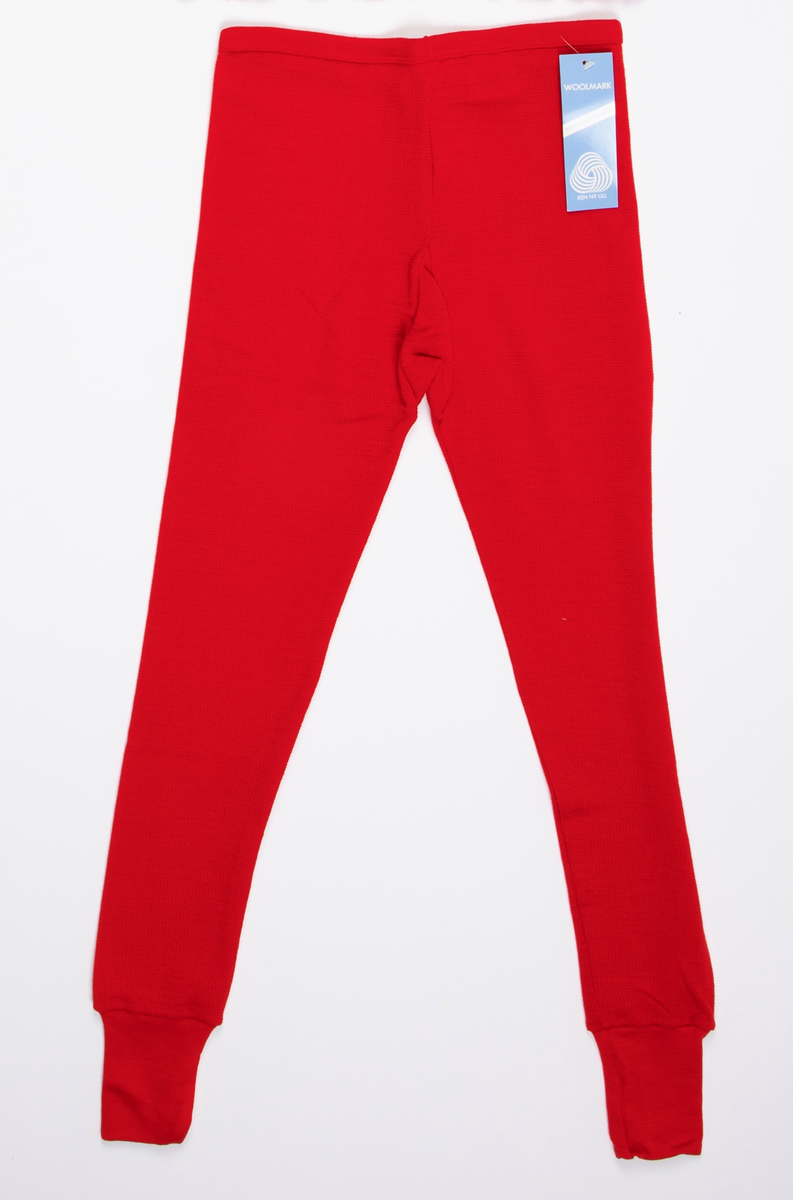 Longs i mønsterstrikket rødt ullgarn. Strikk i livet. Lange ben, trange ved ankelen med påsydd dobbelt glattstrikk. En søm på innsiden av hvert ben.