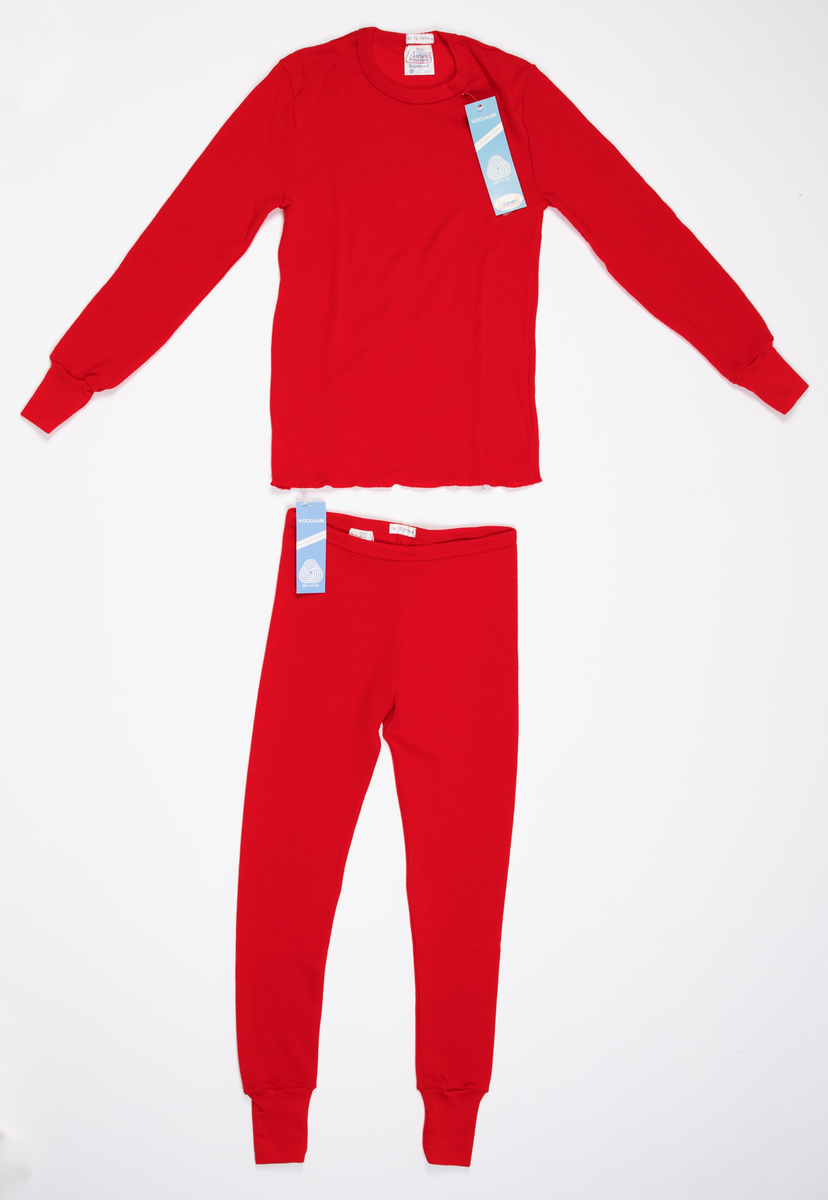 Longs i mønsterstrikket rødt ullgarn. Strikk i livet. Lange ben, trange ved ankelen med påsydd dobbelt glattstrikk. En søm på innsiden av hvert ben.