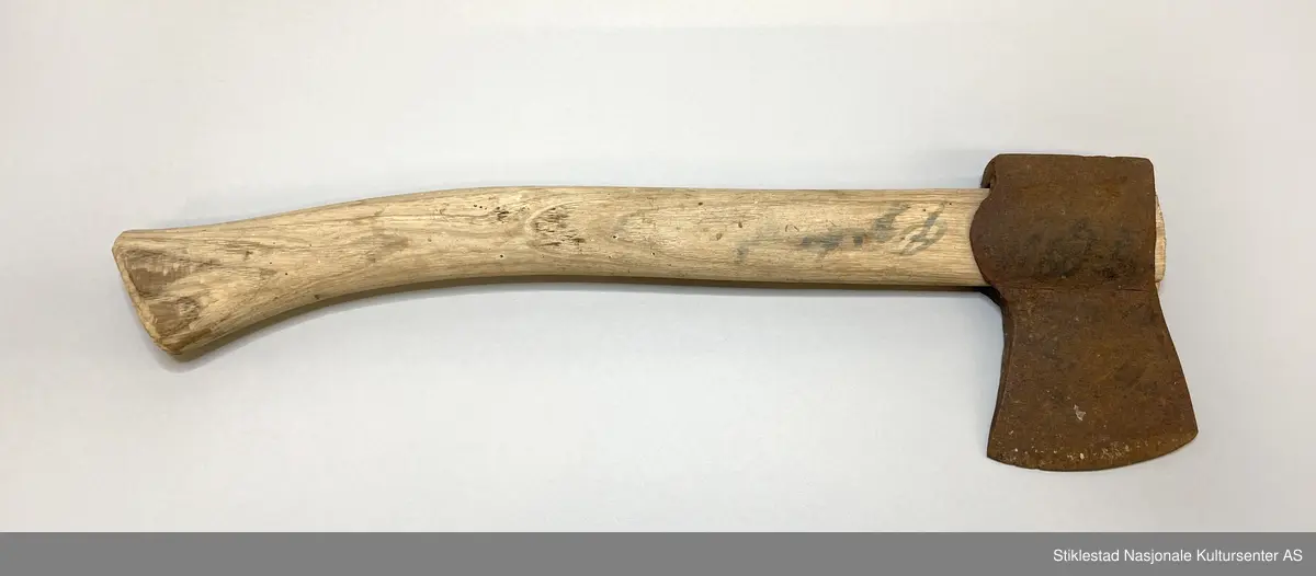 Lita øks, turøks? med nyere skaft (gjenbruk) merket Øgstad med blå sprittusj. Skaft i løvtre. Rustet økseblad.