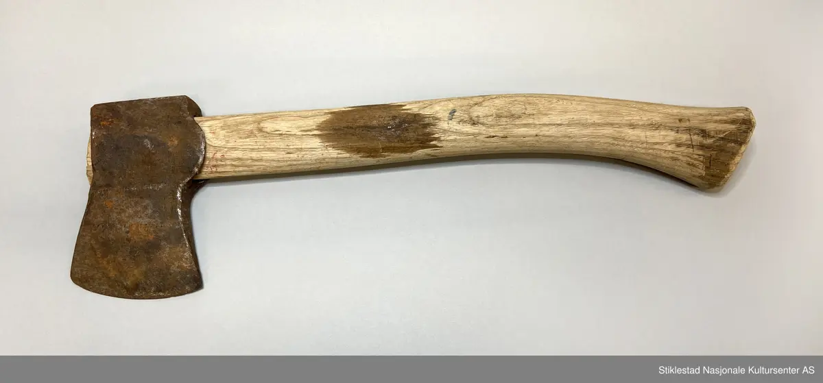 Lita øks, turøks? med nyere skaft (gjenbruk) merket Øgstad med blå sprittusj. Skaft i løvtre. Rustet økseblad.
