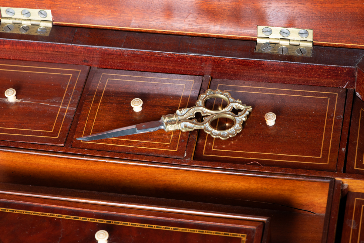 Søyle på firebenet fot. Åttekantet plate med en innlagt stripe med sitrontre langs kanten. Lite nøkkelskilt i sargen. Under platen inndelt i rom med løse lokk. Disse har  innlagte kantstriper og benknotter.
