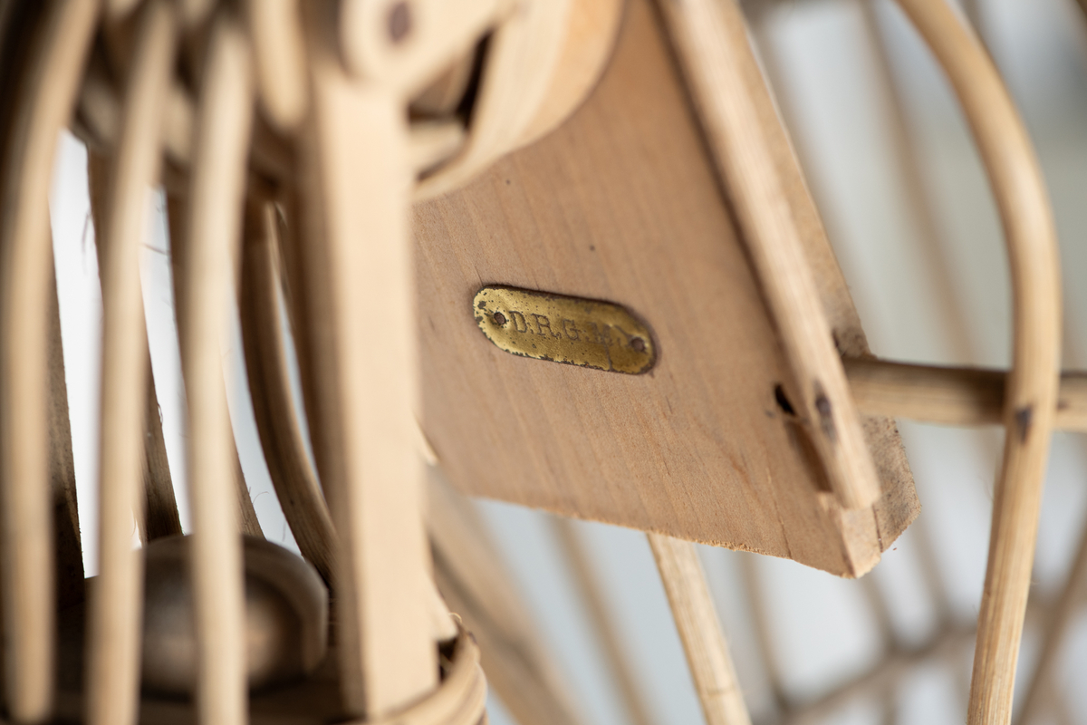 Skjelett  av trespiler, sortmalte  treføtter, lysbrune hender av tre. Kan sette på hode av voks. Skjelett med innsvunget talje, bevegelige armer, massive  føtter. Original etikett henger inni dukken.