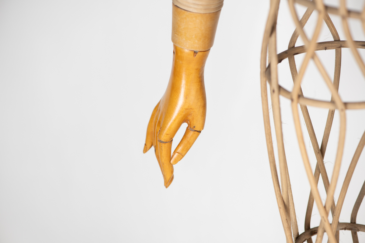 Skjelett  av trespiler, sortmalte  treføtter, lysbrune hender av tre. Kan sette på hode av voks. Skjelett med innsvunget talje, bevegelige armer, massive  føtter. Original etikett henger inni dukken.