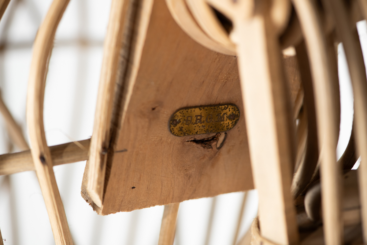 Skjelett  av trespiler, sortmalte  treføtter, lysbrune hender av tre. Kan sette på hode av voks. Skjelett med innsvunget talje, bevegelige armer, massive  føtter. Original etikett henger inni dukken.