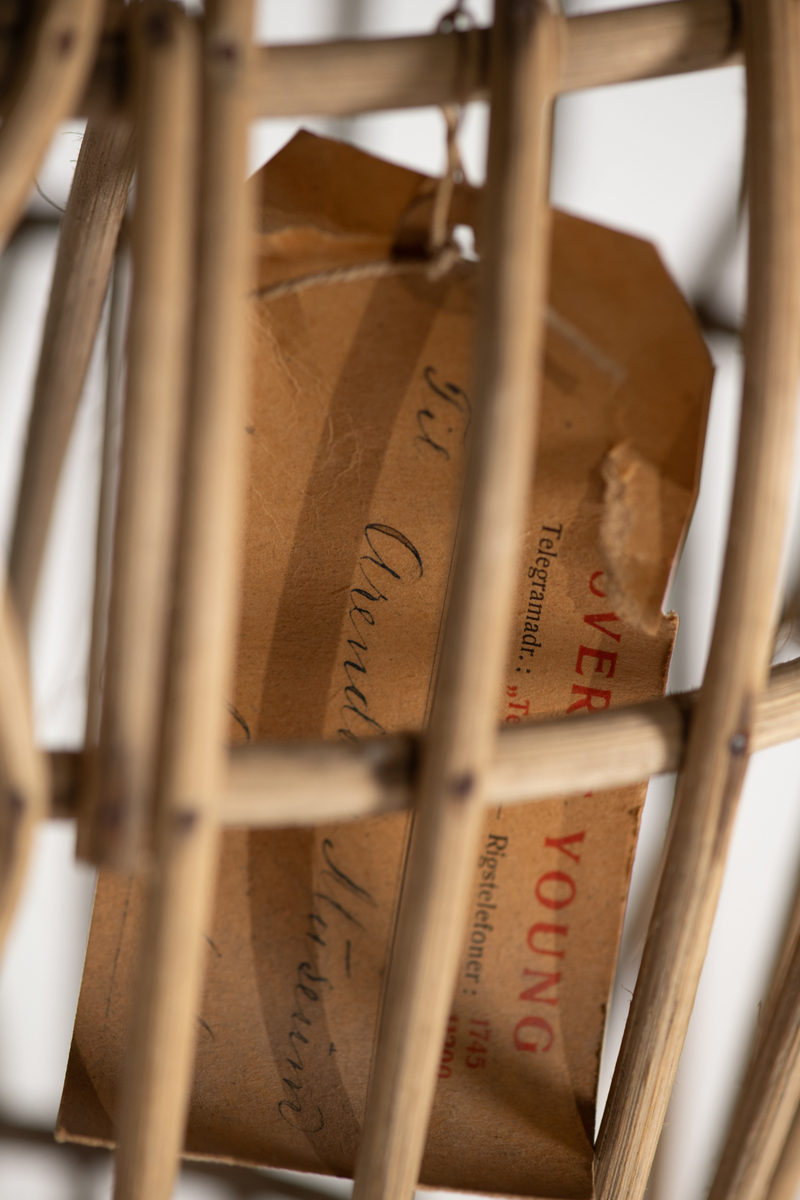 Skjelett  av trespiler, sortmalte  treføtter, lysbrune hender av tre. Kan sette på hode av voks. Skjelett med innsvunget talje, bevegelige armer, massive  føtter. Original etikett henger inni dukken.