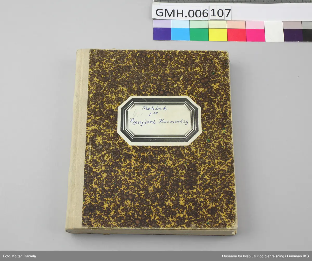 Møteboka for Rypefjord Husmorlag er et linjert notatbok med solid pappomslag med gulbrunt mønster. På forsiden er det påført en åttekantet etikett. Boka har en beige, tekstilforsterket rygg og er velholdt og i god stand.