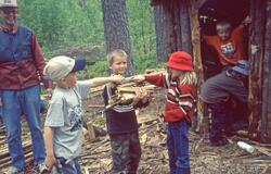 Barnehagebarn bærer ved, ved lavvoen på Slettehefta i Sigdal
