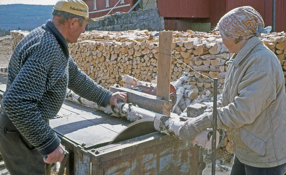 Vedkapping på østre Blekaberg. Han skjærer, hun tar imot vedkubben. 1980- eller 90-årene.