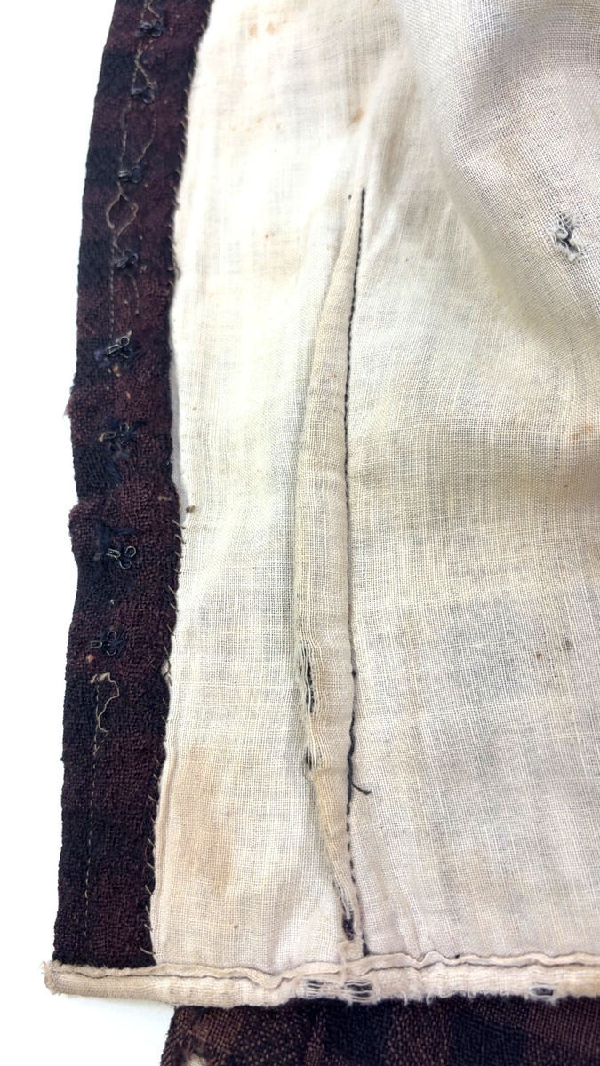 Kjoleliv i svart og brunrutet ull i hjemmevevd toskaft med ermer og bol i samme stoff. Livet er i dag velbrukt, falmet og slitt, med hull på albuene. Sydd for maskin og hånd med panelsøm og bakovertrekte skuldersømmer og sidesømmer. Rund rigning i halsen og buet fremkant. 1,5 cm bred halslinning sydd med maskin og lagt over og festet med faldesting og prikkesting i svart bomullstråd. Tett lukket med 13 par metallhekter med en 1,5 cm bred stolpe som skjuler hektingen. Kantene fremme er først sydd med maskin med brun sytråd og med leggsøm med brun bomullstråd. Livet har et innsnitt som er 3 cm på det bredeste under bysten, sydd med maskin. Smal tosøms krokarm. Livet er helfôret med ubleket bomull i hjemmevevd toskaft og sydd på samtidig som ullstoffet ble sydd sammen med maskin og spilesøm med tykk bomullstråd for hånd. Livet brukes ned i stakken og har hatt en metallkrok midt på bak til å hekte stakken på.