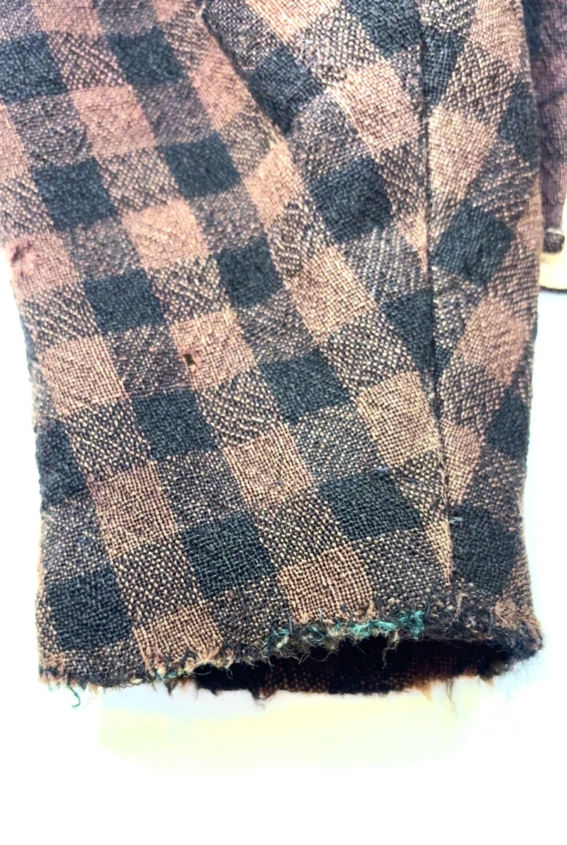 Kjoleliv i svart og brunrutet ull i hjemmevevd toskaft med ermer og bol i samme stoff. Livet er i dag velbrukt, falmet og slitt, med hull på albuene. Sydd for maskin og hånd med panelsøm og bakovertrekte skuldersømmer og sidesømmer. Rund rigning i halsen og buet fremkant. 1,5 cm bred halslinning sydd med maskin og lagt over og festet med faldesting og prikkesting i svart bomullstråd. Tett lukket med 13 par metallhekter med en 1,5 cm bred stolpe som skjuler hektingen. Kantene fremme er først sydd med maskin med brun sytråd og med leggsøm med brun bomullstråd. Livet har et innsnitt som er 3 cm på det bredeste under bysten, sydd med maskin. Smal tosøms krokarm. Livet er helfôret med ubleket bomull i hjemmevevd toskaft og sydd på samtidig som ullstoffet ble sydd sammen med maskin og spilesøm med tykk bomullstråd for hånd. Livet brukes ned i stakken og har hatt en metallkrok midt på bak til å hekte stakken på.