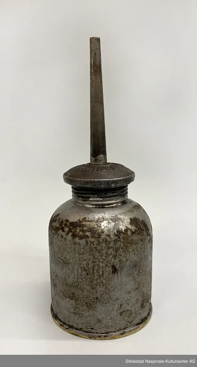 Fabrikkprodusert oljekanne i jernblikk? med rund oljebeholder. Skrukork med tut. Mulig kork er uoriginal. En god del oljesøl.