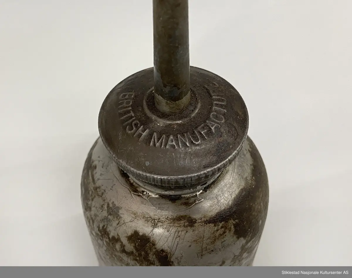 Fabrikkprodusert oljekanne i jernblikk? med rund oljebeholder. Skrukork med tut. Mulig kork er uoriginal. En god del oljesøl.