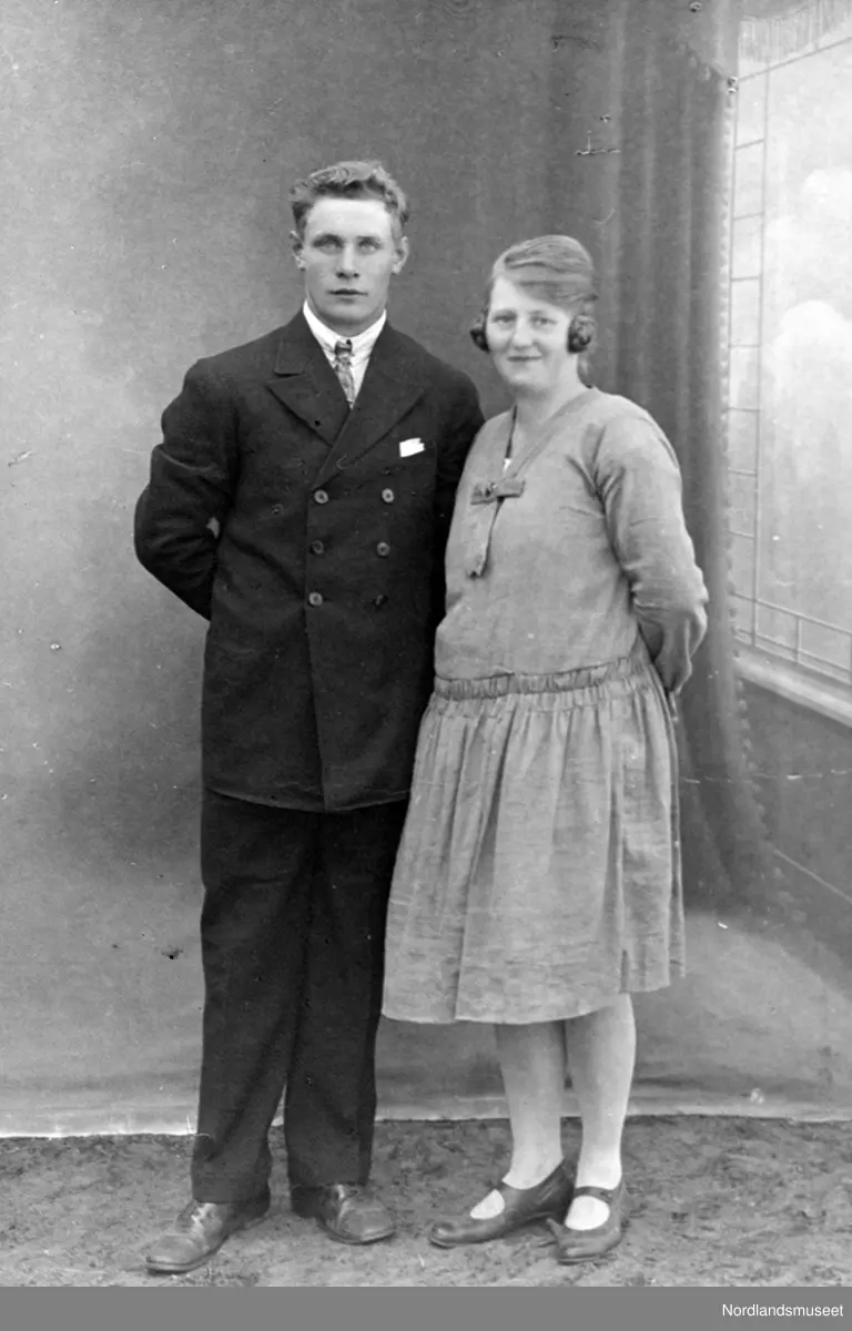 Portrett av et ektepar. Damen har kjole med hoftebelte, sko med rem. Mannen i dress.