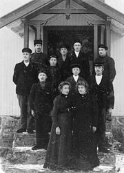 11 personer på ei trapp. Alle har mørke klær.