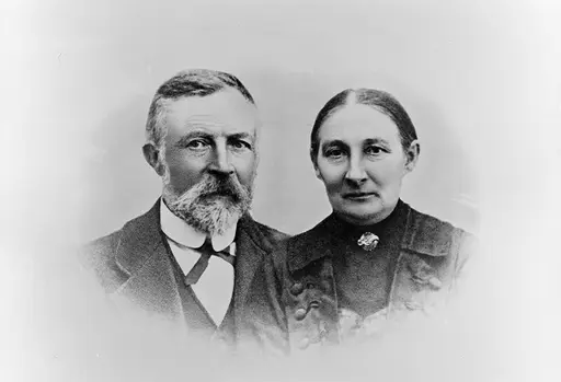 Portrett av mann med skjegg og bart, dame med glatt hår, midtskill og brystnål.