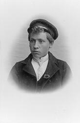 Portrett av mann med kasjettlue, hvit skjorte og slips.