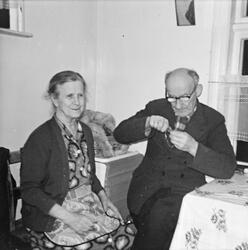 Portrett av en dame med glatt hår og en mann med briller. Be