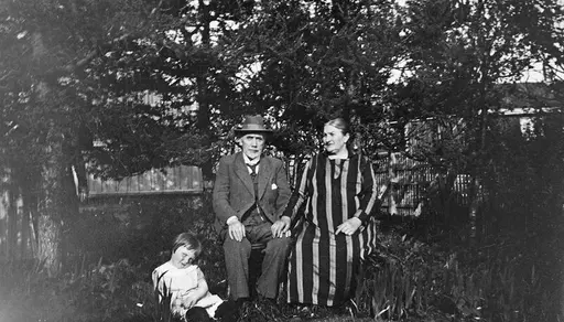 Et barn og et eldre par sittende i en hage, han har hatt.