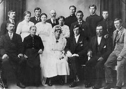 Brudebilde med brudeparet sittende foran i midten og mange p