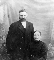 Portrett av en mann med skjegg som står ved siden av en sitt