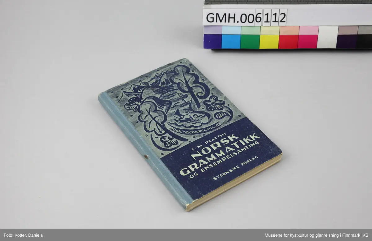 Liten bok med pappomslag. Forsiden av boka er dekorert i tre forskjellige blånyanser. Bildet viser en fjord hvor en nordlandsbåt seiler med råseil, omgitt av fisker som stikker opp av vannet. Omkring er det blomster, trær, åser og fjell. Under står tittelen med lyseblå bokstaver på mørkeblå bakgrunn. På baksiden reklameres det for andre utgivelser av P.M. Bye & Co. A.S, Oslo.  Bokas rygg er beskyttet med lett mønstret, blått papir og er bundet sammen med trådbinding.