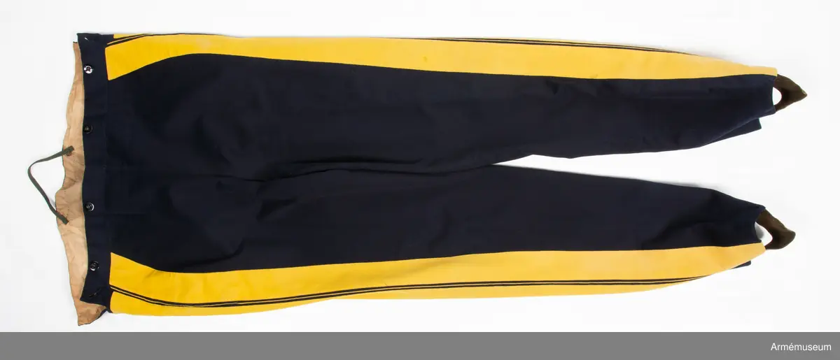 Mörkblå långbyxor med dubbla gula revärer i sidorna.

Byxorna är sydda av fint mörkblått kläde och är konstruerade med två fram- och två bakstycken, ett litet ok bak och hel lucka fram som knäpps i varje sida med en knapp. I varje sida av luckan sitter vidare en spänntamp fodrad med brunt linne- eller hampatyg som är avsedd att spännas ihop baktill för att reglera midjevidden.
Byxorna är ofodrade men har infodring i midjan och i luckan av oblekt linne- eller hampatyg, och ovanpå detta ytterligare en (troligen sekundär) infodring av oblekt bomullstyg. De har sytts om vid minst ett tillfälle då en mycket bred kil har satts in i grensömmen bak för att öka vidden.
Inuti byxorna sitter en förstärkning av oblekt bomullstyg i grenen. I byxbenens sidor sitter ca 5 cm breda dubbla revärer av fint gult kläde med en smal passpoal av gult kläde mellan. Nertill i fållen av varje ben sitter fastsydda ca 7-8 cm breda hälremmar av brunt skinn, samt på benens insida framtill en förstärkning av oblekt linne- eller hampatyg. Byxorna har fyra knappar fram i linningen och två bak för fastsättning av hängslen. Samtliga knappar är av svartlackad metall.
Byxorna har påskrift med svart bläck på luckans insida:
"46,371. Tillh. Genereallöjt. M. Thulstrup. G. af. enkefru H. C. Thulstrup".
