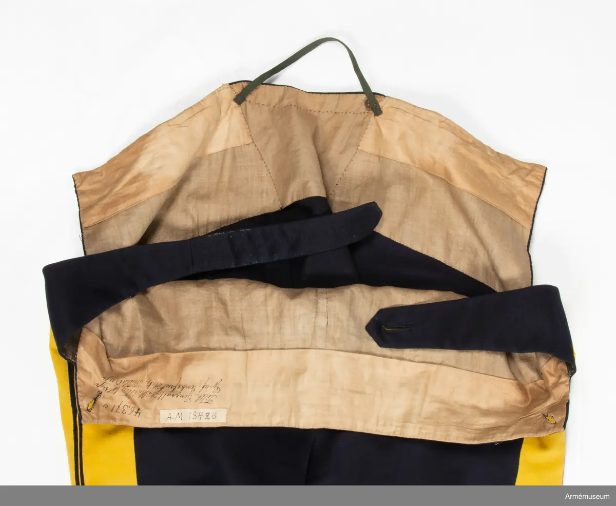 Mörkblå långbyxor med dubbla gula revärer i sidorna.

Byxorna är sydda av fint mörkblått kläde och är konstruerade med två fram- och två bakstycken, ett litet ok bak och hel lucka fram som knäpps i varje sida med en knapp. I varje sida av luckan sitter vidare en spänntamp fodrad med brunt linne- eller hampatyg som är avsedd att spännas ihop baktill för att reglera midjevidden.
Byxorna är ofodrade men har infodring i midjan och i luckan av oblekt linne- eller hampatyg, och ovanpå detta ytterligare en (troligen sekundär) infodring av oblekt bomullstyg. De har sytts om vid minst ett tillfälle då en mycket bred kil har satts in i grensömmen bak för att öka vidden.
Inuti byxorna sitter en förstärkning av oblekt bomullstyg i grenen. I byxbenens sidor sitter ca 5 cm breda dubbla revärer av fint gult kläde med en smal passpoal av gult kläde mellan. Nertill i fållen av varje ben sitter fastsydda ca 7-8 cm breda hälremmar av brunt skinn, samt på benens insida framtill en förstärkning av oblekt linne- eller hampatyg. Byxorna har fyra knappar fram i linningen och två bak för fastsättning av hängslen. Samtliga knappar är av svartlackad metall.
Byxorna har påskrift med svart bläck på luckans insida:
"46,371. Tillh. Genereallöjt. M. Thulstrup. G. af. enkefru H. C. Thulstrup".