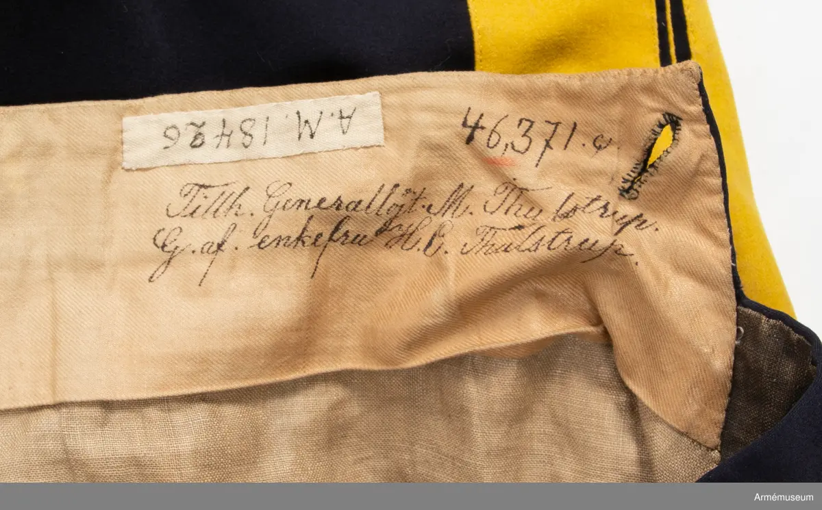 Mörkblå långbyxor med dubbla gula revärer i sidorna.

Byxorna är sydda av fint mörkblått kläde och är konstruerade med två fram- och två bakstycken, ett litet ok bak och hel lucka fram som knäpps i varje sida med en knapp. I varje sida av luckan sitter vidare en spänntamp fodrad med brunt linne- eller hampatyg som är avsedd att spännas ihop baktill för att reglera midjevidden.
Byxorna är ofodrade men har infodring i midjan och i luckan av oblekt linne- eller hampatyg, och ovanpå detta ytterligare en (troligen sekundär) infodring av oblekt bomullstyg. De har sytts om vid minst ett tillfälle då en mycket bred kil har satts in i grensömmen bak för att öka vidden.
Inuti byxorna sitter en förstärkning av oblekt bomullstyg i grenen. I byxbenens sidor sitter ca 5 cm breda dubbla revärer av fint gult kläde med en smal passpoal av gult kläde mellan. Nertill i fållen av varje ben sitter fastsydda ca 7-8 cm breda hälremmar av brunt skinn, samt på benens insida framtill en förstärkning av oblekt linne- eller hampatyg. Byxorna har fyra knappar fram i linningen och två bak för fastsättning av hängslen. Samtliga knappar är av svartlackad metall.
Byxorna har påskrift med svart bläck på luckans insida:
"46,371. Tillh. Genereallöjt. M. Thulstrup. G. af. enkefru H. C. Thulstrup".