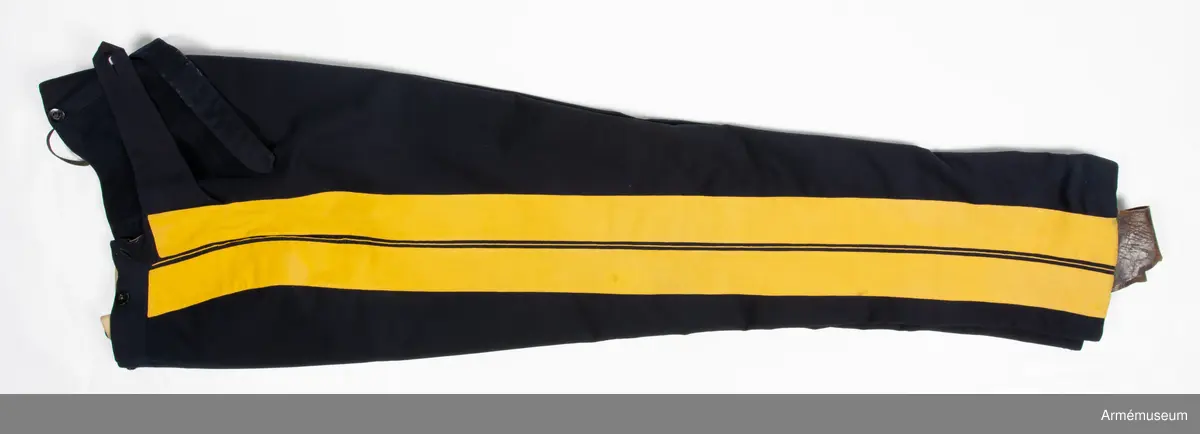 Mörkblå långbyxor med dubbla gula revärer i sidorna.

Byxorna är sydda av fint mörkblått kläde och är konstruerade med två fram- och två bakstycken, ett litet ok bak och hel lucka fram som knäpps i varje sida med en knapp. I varje sida av luckan sitter vidare en spänntamp fodrad med brunt linne- eller hampatyg som är avsedd att spännas ihop baktill för att reglera midjevidden.
Byxorna är ofodrade men har infodring i midjan och i luckan av oblekt linne- eller hampatyg, och ovanpå detta ytterligare en (troligen sekundär) infodring av oblekt bomullstyg. De har sytts om vid minst ett tillfälle då en mycket bred kil har satts in i grensömmen bak för att öka vidden.
Inuti byxorna sitter en förstärkning av oblekt bomullstyg i grenen. I byxbenens sidor sitter ca 5 cm breda dubbla revärer av fint gult kläde med en smal passpoal av gult kläde mellan. Nertill i fållen av varje ben sitter fastsydda ca 7-8 cm breda hälremmar av brunt skinn, samt på benens insida framtill en förstärkning av oblekt linne- eller hampatyg. Byxorna har fyra knappar fram i linningen och två bak för fastsättning av hängslen. Samtliga knappar är av svartlackad metall.
Byxorna har påskrift med svart bläck på luckans insida:
"46,371. Tillh. Genereallöjt. M. Thulstrup. G. af. enkefru H. C. Thulstrup".