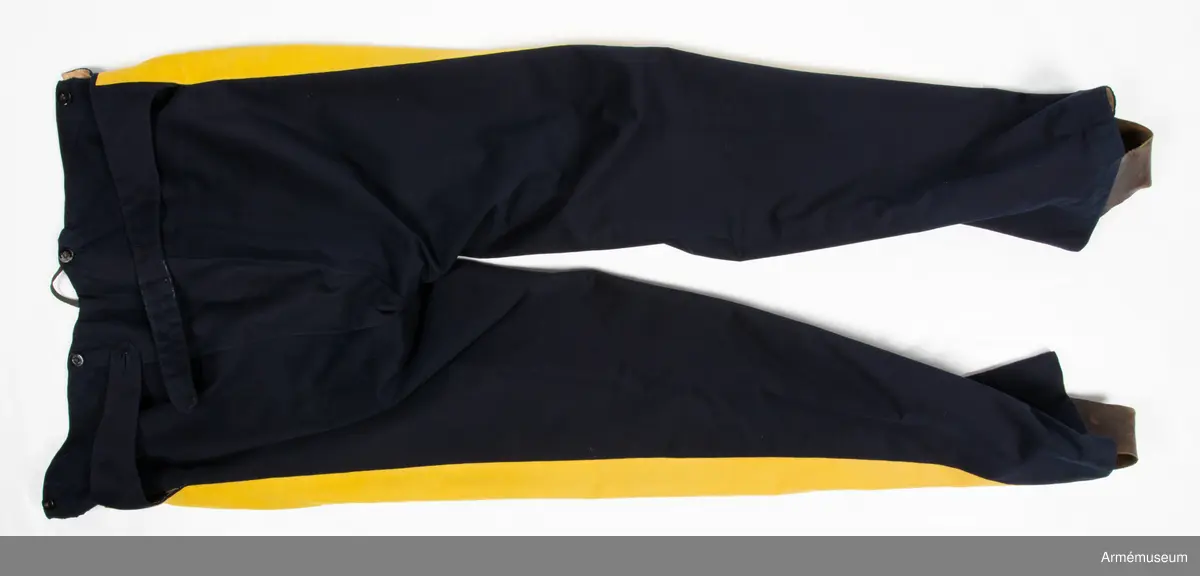 Mörkblå långbyxor med dubbla gula revärer i sidorna.

Byxorna är sydda av fint mörkblått kläde och är konstruerade med två fram- och två bakstycken, ett litet ok bak och hel lucka fram som knäpps i varje sida med en knapp. I varje sida av luckan sitter vidare en spänntamp fodrad med brunt linne- eller hampatyg som är avsedd att spännas ihop baktill för att reglera midjevidden.
Byxorna är ofodrade men har infodring i midjan och i luckan av oblekt linne- eller hampatyg, och ovanpå detta ytterligare en (troligen sekundär) infodring av oblekt bomullstyg. De har sytts om vid minst ett tillfälle då en mycket bred kil har satts in i grensömmen bak för att öka vidden.
Inuti byxorna sitter en förstärkning av oblekt bomullstyg i grenen. I byxbenens sidor sitter ca 5 cm breda dubbla revärer av fint gult kläde med en smal passpoal av gult kläde mellan. Nertill i fållen av varje ben sitter fastsydda ca 7-8 cm breda hälremmar av brunt skinn, samt på benens insida framtill en förstärkning av oblekt linne- eller hampatyg. Byxorna har fyra knappar fram i linningen och två bak för fastsättning av hängslen. Samtliga knappar är av svartlackad metall.
Byxorna har påskrift med svart bläck på luckans insida:
"46,371. Tillh. Genereallöjt. M. Thulstrup. G. af. enkefru H. C. Thulstrup".