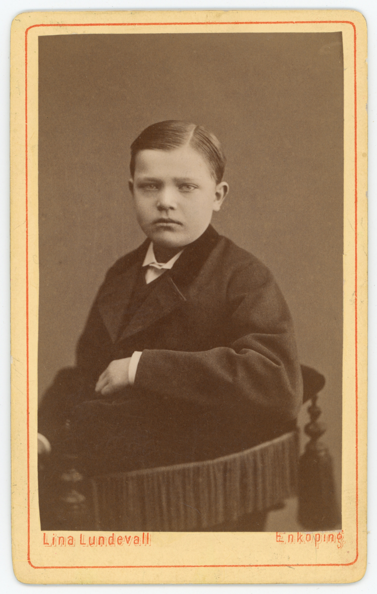 Svartvit ateljéporträtt av okänd pojke.