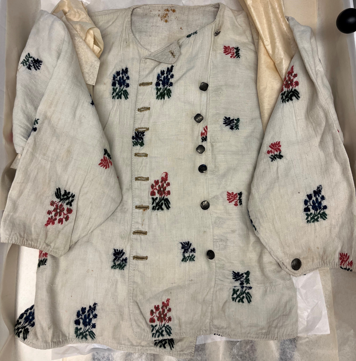 Form: Sølvknappane er runde og firkanta.
1 tröie.

Tröie, vævet av hvit lin. Har overalt utvendig paa-broderte blomster av blaat, rödt og brunt uldgarn. Runde og firkantete sølvknapper. 
Begge disse no. (7090 og 7091) skal stamme fra Lund prestegjeld, S. Bergenhusamt.

Kjöpt av handelsreisende Agrim Hove, Bergen.