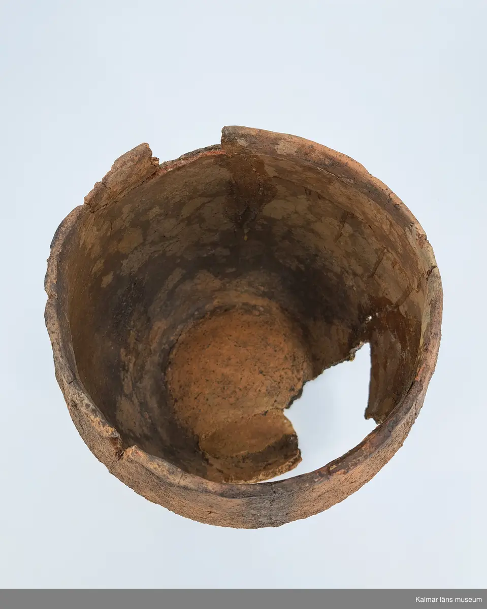 KLM 6315. Gravurna, nästan komplett urna. Höjd 28 cm, Mynningsdiameter 19 cm, Godstjocklek ca 8 mm. Tunnformad fint rabbad kruka med aningen övervikt mynning. Magrad med krossad granit. Oxiderat bränd (syrerik miljö). Grovt lerkärl utan öra.