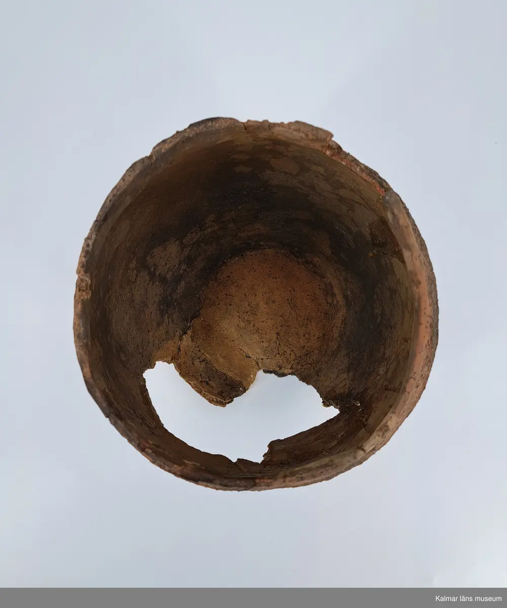 KLM 6315. Gravurna, nästan komplett urna. Höjd 28 cm, Mynningsdiameter 19 cm, Godstjocklek ca 8 mm. Tunnformad fint rabbad kruka med aningen övervikt mynning. Magrad med krossad granit. Oxiderat bränd (syrerik miljö). Grovt lerkärl utan öra.