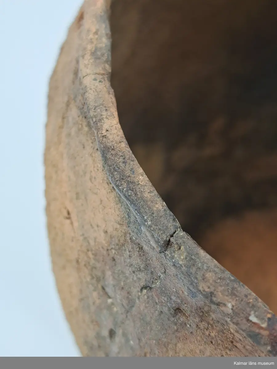 KLM 6315. Gravurna, nästan komplett urna. Höjd 28 cm, Mynningsdiameter 19 cm, Godstjocklek ca 8 mm. Tunnformad fint rabbad kruka med aningen övervikt mynning. Magrad med krossad granit. Oxiderat bränd (syrerik miljö). Grovt lerkärl utan öra.