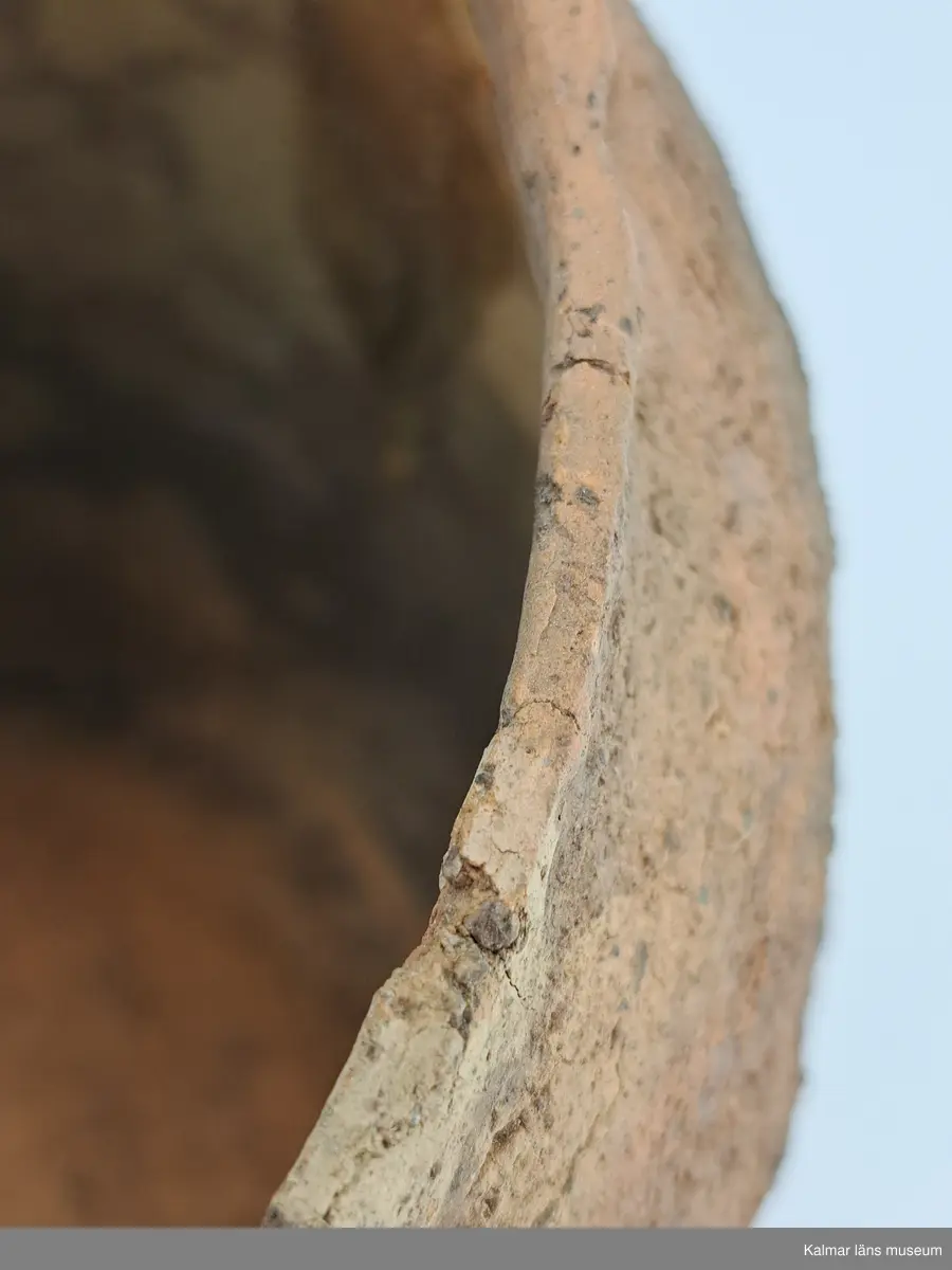 KLM 6315. Gravurna, nästan komplett urna. Höjd 28 cm, Mynningsdiameter 19 cm, Godstjocklek ca 8 mm. Tunnformad fint rabbad kruka med aningen övervikt mynning. Magrad med krossad granit. Oxiderat bränd (syrerik miljö). Grovt lerkärl utan öra.