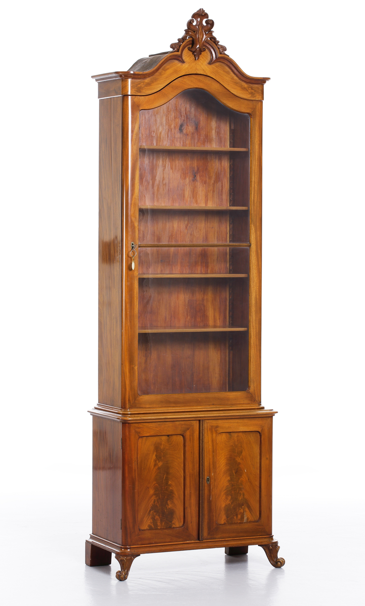 Vitrinskåp av mahogy, i två delar. Överskåp med snidat krönornament, fyra hyllor och glasdörrar, undre skåpdel med två trädörrar. Skåpet har brukats för förvaring av böcker och småsaker.
Inskrivet i huvudkatalog 1969.