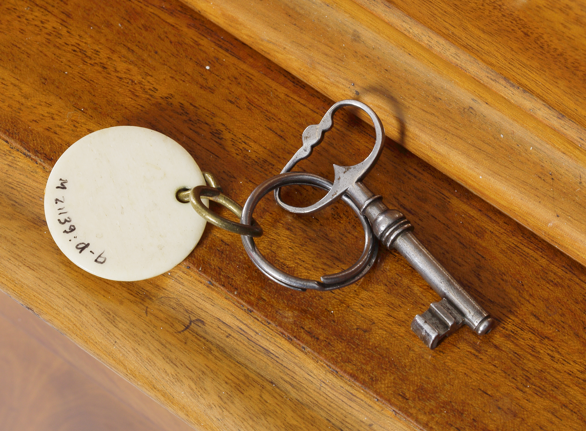 Vitrinskåp av mahogy, i två delar. Överskåp med snidat krönornament, fyra hyllor och glasdörrar, undre skåpdel med två trädörrar. Skåpet har brukats för förvaring av böcker och småsaker.
Inskrivet i huvudkatalog 1969.