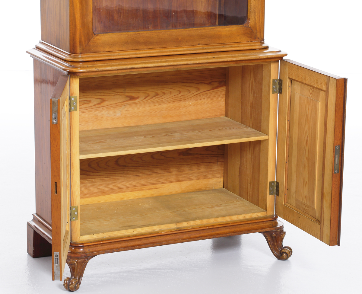 Vitrinskåp av mahogy, i två delar. Överskåp med snidat krönornament, fyra hyllor och glasdörrar, undre skåpdel med två trädörrar. Skåpet har brukats för förvaring av böcker och småsaker.
Inskrivet i huvudkatalog 1969.