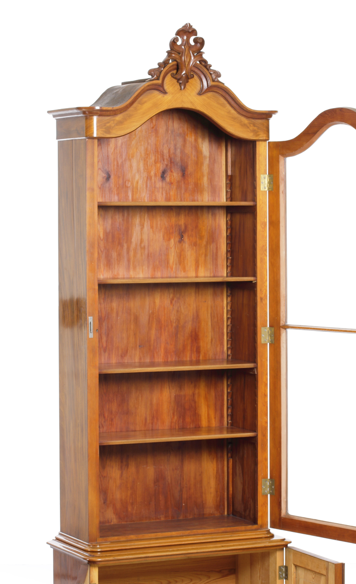 Vitrinskåp av mahogy, i två delar. Överskåp med snidat krönornament, fyra hyllor och glasdörrar, undre skåpdel med två trädörrar. Skåpet har brukats för förvaring av böcker och småsaker.
Inskrivet i huvudkatalog 1969.