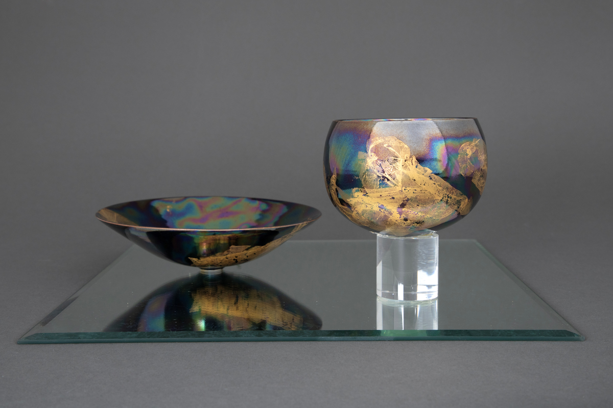 En skål og fire boller i porselen, montert på to kvadratiske speil. På det ene speilet står skålen samt en av bollene på en sylinderformet sokkel i klart glass. På det andre speilet står tre boller, to av dem på sylinderformede sokler i klart glass.