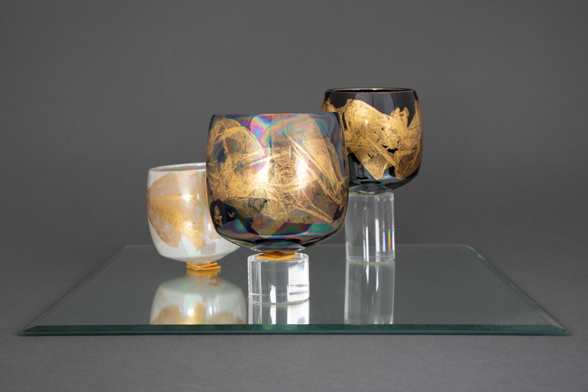 En skål og fire boller i porselen, montert på to kvadratiske speil. På det ene speilet står skålen samt en av bollene på en sylinderformet sokkel i klart glass. På det andre speilet står tre boller, to av dem på sylinderformede sokler i klart glass.