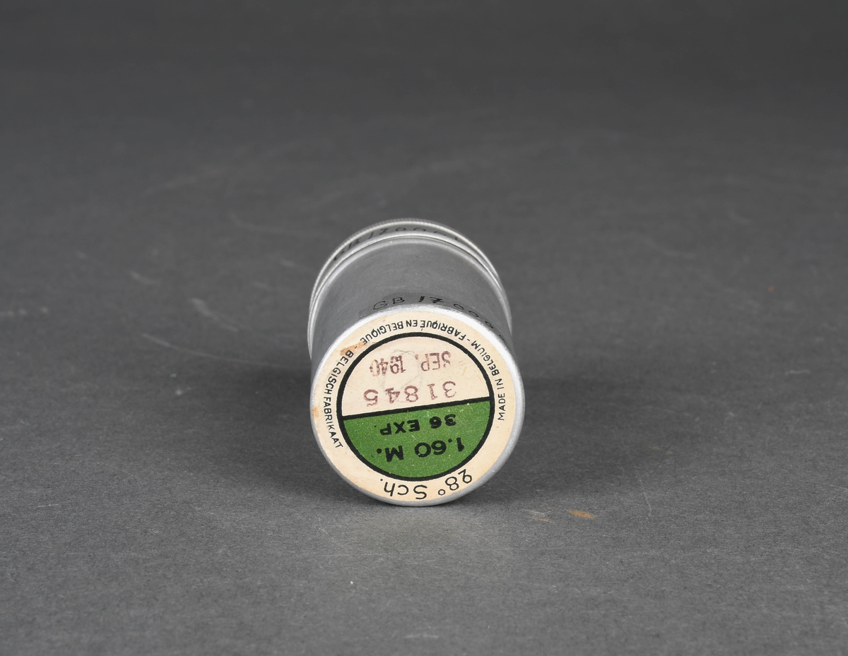 Sylindrisk beholder i metall. Todelt med stort hovedrom og mindre lokk. Lukkemekanisme består av gjenger.