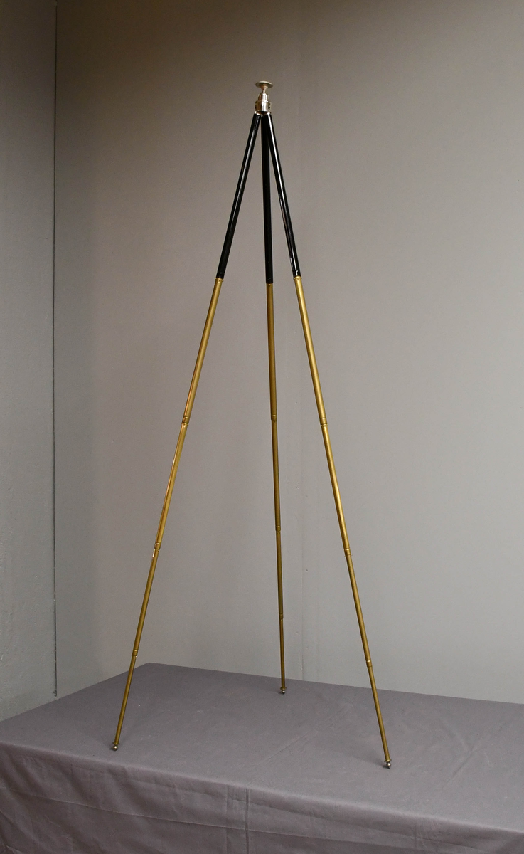 Fotostativ av metall og messing. Sortmalt øverst. Tripod. Utrekkbare bein, fem ledd.