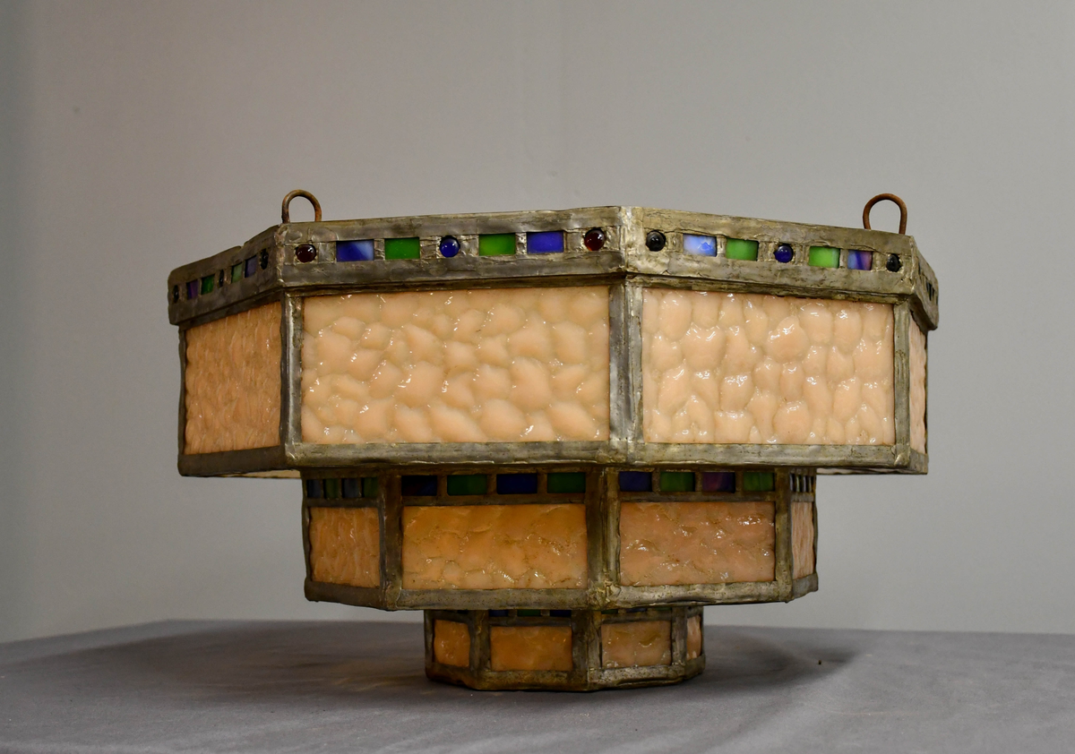 Åttekantet lampeskjerm av blyglass. Farget glass. Bygd opp i tre etasjer, smalner nedover. Fire blykroker loddet fast øverst. Åttetagget stjerne nedderst.