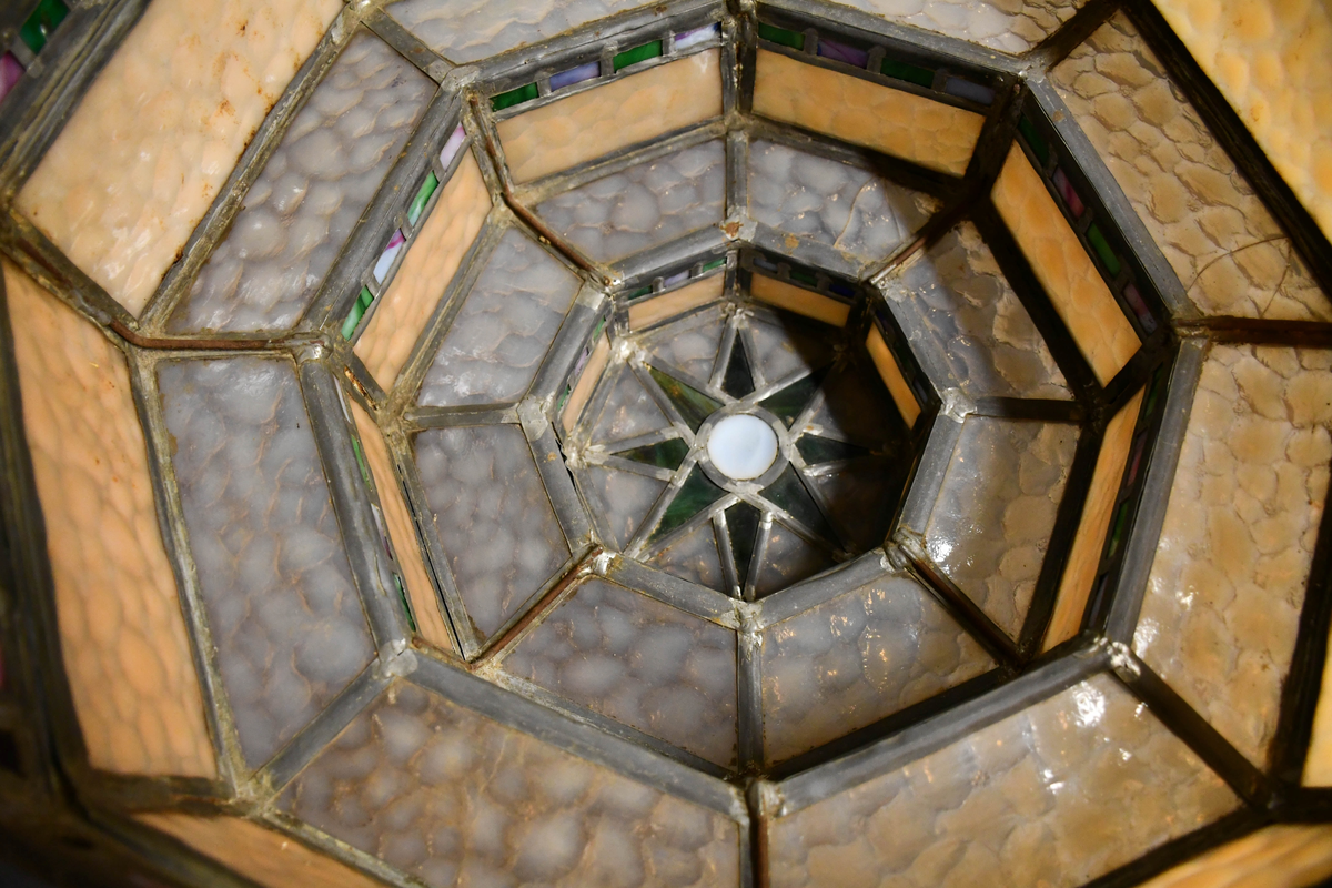 Åttekantet lampeskjerm av blyglass. Farget glass. Bygd opp i tre etasjer, smalner nedover. Fire blykroker loddet fast øverst. Åttetagget stjerne nedderst.