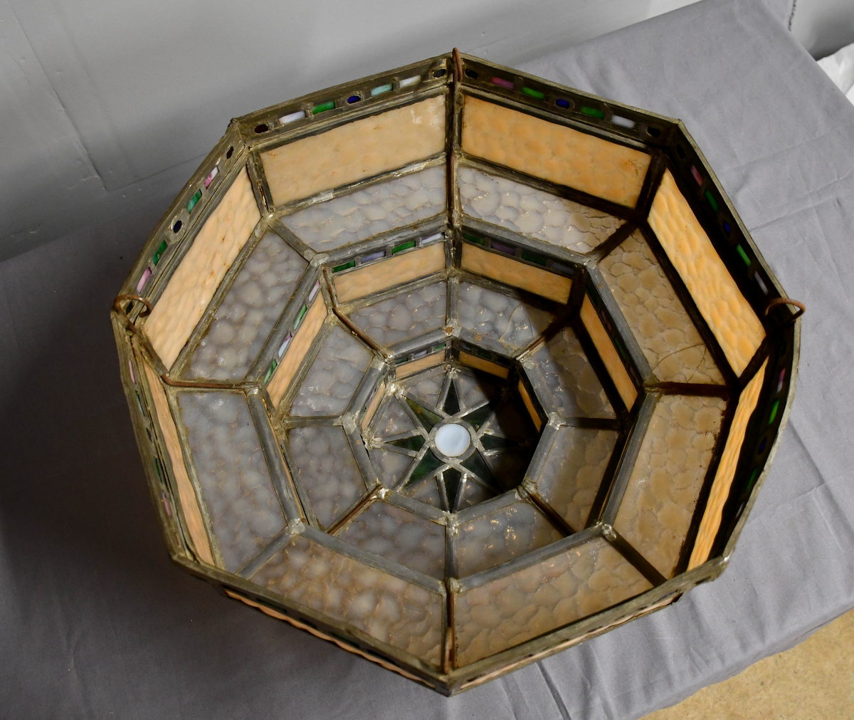 Åttekantet lampeskjerm av blyglass. Farget glass. Bygd opp i tre etasjer, smalner nedover. Fire blykroker loddet fast øverst. Åttetagget stjerne nedderst.